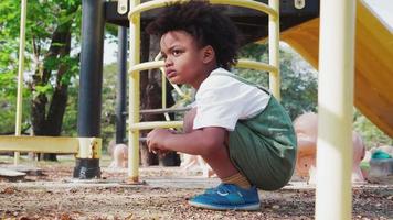 niedlicher kleiner Afroamerikanerkindjunge, der Spaß beim Spielen auf dem Spielplatz tagsüber im Sommer hat. video