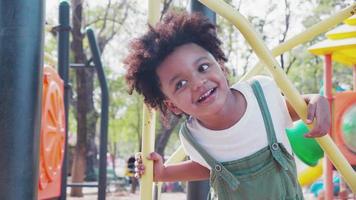 niedlicher afroamerikanischer kleiner Junge, der Spaß hat, während er tagsüber im Sommer auf dem Spielplatz spielt. video