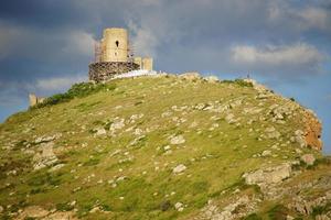 Vista de la fortaleza genovesa en la ladera de una montaña con un nublado cielo azul en Crimea