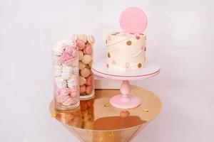 Beautiful birthday cake with pink decor for the birthday of a child. Candy bar with macaroons and marshmallows. photo