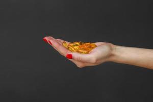 Scattering transparent yellow pills. A handful of capsules in the palm of a hand, close-up, isolated on gray background. Capsules fish oil, omega 3. Healthy lifestyle, dietary nutritional supplements.