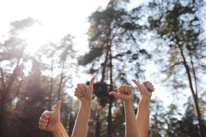 Human hands showing thumbs up isolated on a natural background. Male and female hands showing OK signs in the park. Selective focus. Copy space. photo