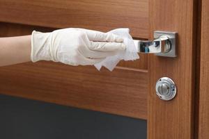 Person disinfects and cleans door handle with anti-bacterial wet wipes to protect against viruses, germs, and bacteria during coronavirus outbreak and covid epidemic. Clean home. photo