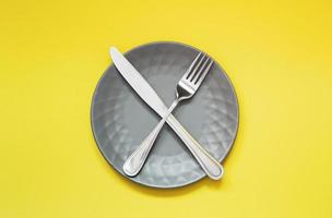 Empty gray plate and cutlery on yellow background photo