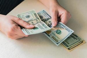 Woman's hands counting dollar bills on white desk photo
