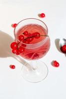 Pink champagne wine jelly with red currant in a glass, bright daylight, on white background. Top view. Copy space. photo