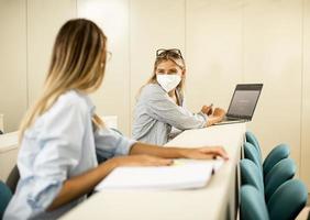 Female student wearing face protective medical mask for virus protection at lecture hall photo