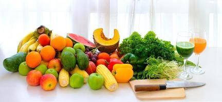 Surtido de frutas y verduras frescas maduras sobre la mesa con fondo de cortina blanca foto