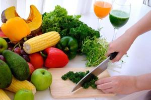 Hands using a knife chopping vegetables over wooden carving board photo
