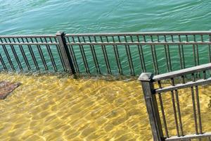 Flooded embankment next to a metal fence at the Angara River in Irkutsk photo