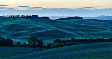 Amanecer sobre colinas con curvas en Toscana