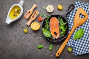 Salmon filet in old cast iron skillet on dark stone background photo