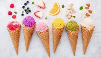 Various of ice cream flavors in cones on white stone background photo