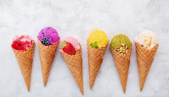 Various of ice cream flavors in cones on white stone background photo