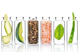 Cuidado de la piel alternativo con ingredientes naturales en botellas de vidrio aislado sobre fondo blanco.