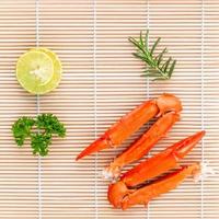 Boiled crab claws with lime and parsley on bamboo background photo