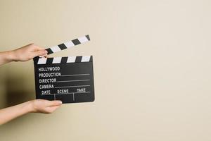 Cropped hands with clapperboard on neutral background