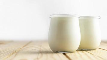 Vista frontal de yogur natural en frascos con iluminación natural. foto