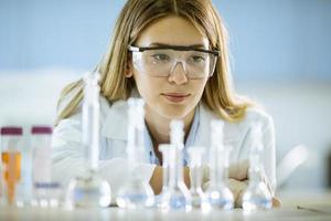 Investigadora científica o médica femenina mirando frascos con soluciones en un laboratorio foto