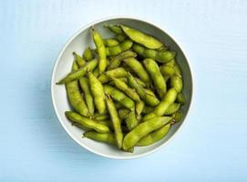 Flat lay edamame beans in bowl on blue background photo