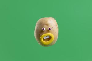 Funny potato with face sticker on spring green background photo