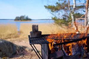 Fire in a rusty vintage grill outdoor on the beach of the sea photo