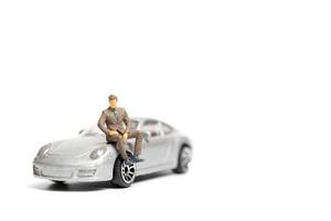 Miniature people, businessman sitting on a car and copy space for text photo