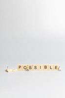 Miniature people, team of workers with the word Impossible in wooden letters with prefix un crossed-out, leaving the word possible photo