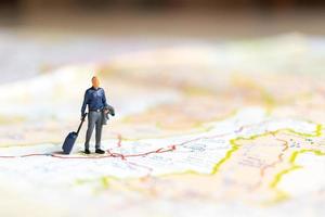 Miniature businessman standing on map, travel concept photo