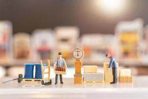 Miniature people, postman officers on duty preparing to send a box to the consumer. Delivery service for e-commerce concept photo