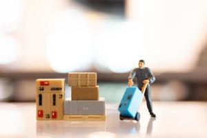 Miniature people, postman officers on duty preparing to send a box to the consumer. Delivery service for e-commerce concept photo