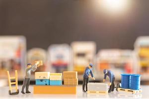 Miniature people, postman officers on duty preparing to send a box to the consumer. Delivery service for e-commerce concept photo