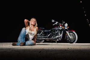 sexy rubia sentada cerca de su motocicleta foto