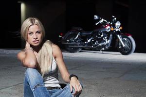 sexy rubia sentada cerca de su motocicleta foto