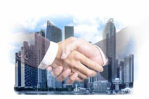 Double exposure of businessmen handshake on a modern city building financial district and commerce, business partnership successful and strategic plan concept photo