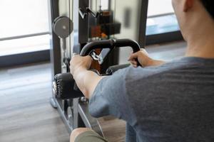 Joven principiante haciendo ejercicio con pesas flexionando los músculos en un gimnasio, concepto de entrenamiento deportivo foto