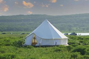 White tent in a field with cloudy blue sky