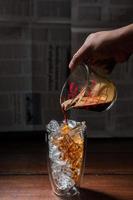 Barista pouring milk into a glass of iced coffee photo