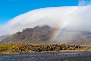 montaña cubierta de una nube blanca con un arco iris