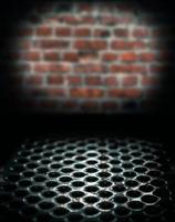Metal perforated table surface in a dark basement against a brick wall, close up horror background photo