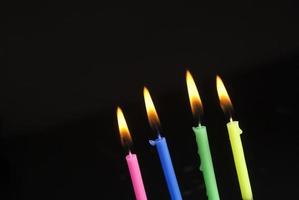 Colorful burning candles on black background photo