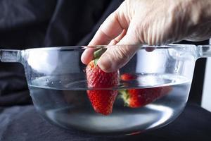 Person putting strawberries in water photo