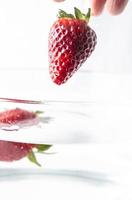 Hand throwing strawberries in water photo