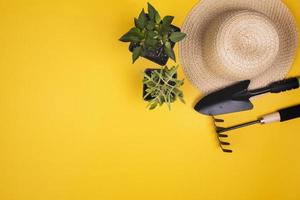 Herramientas de jardinería con sombrero de paja y copie el espacio sobre fondo amarillo