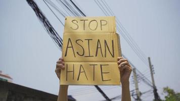 um homem segurando uma placa de ódio asiático pare video