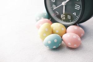 Easter eggs and alarm clock on white background photo