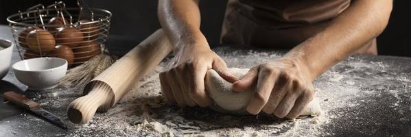Chef usando las manos con harina para amasar la masa