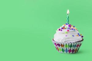 Close-up de delicioso cupcake con velas encendidas sobre fondo verde foto