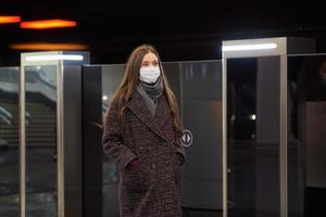 Woman in a medical face mask is standing near the departing train on the subway photo