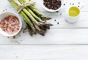 Bunch of raw asparagus stems with different spices photo